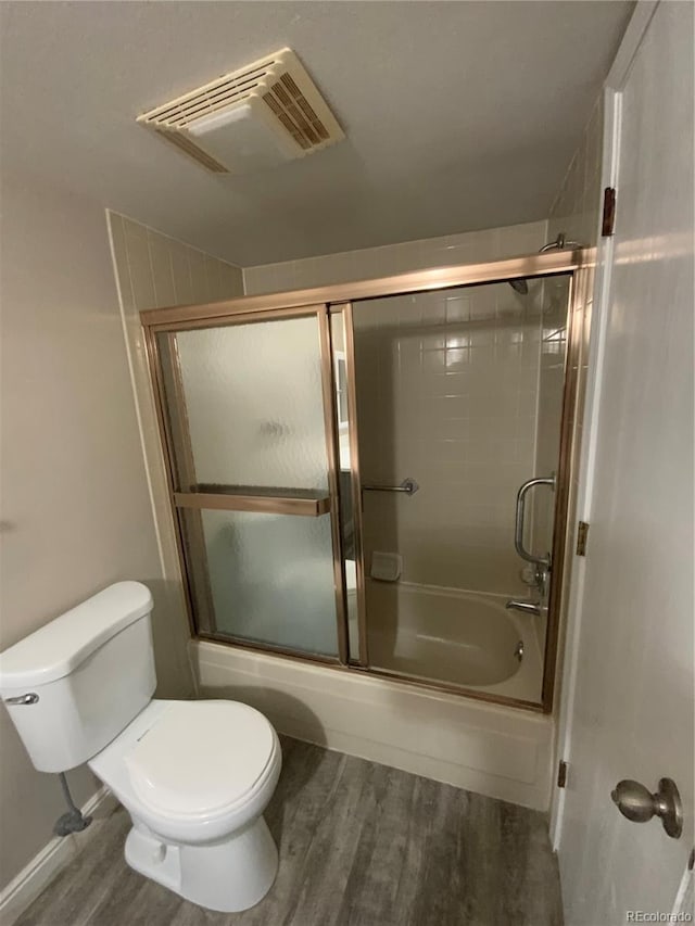 bathroom featuring shower / bath combination with glass door, toilet, and hardwood / wood-style floors