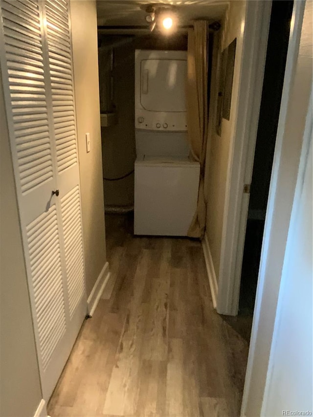 laundry room featuring light wood-type flooring and stacked washing maching and dryer