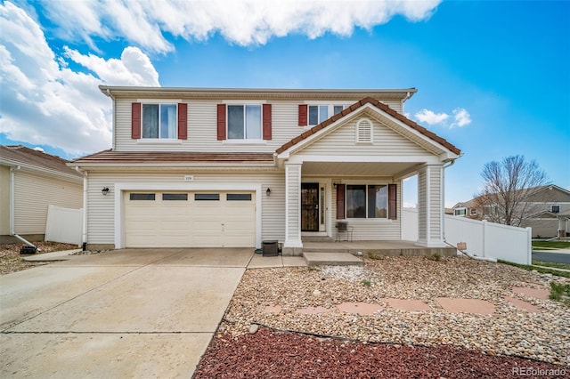 traditional-style home with covered porch, a garage, driveway, and fence