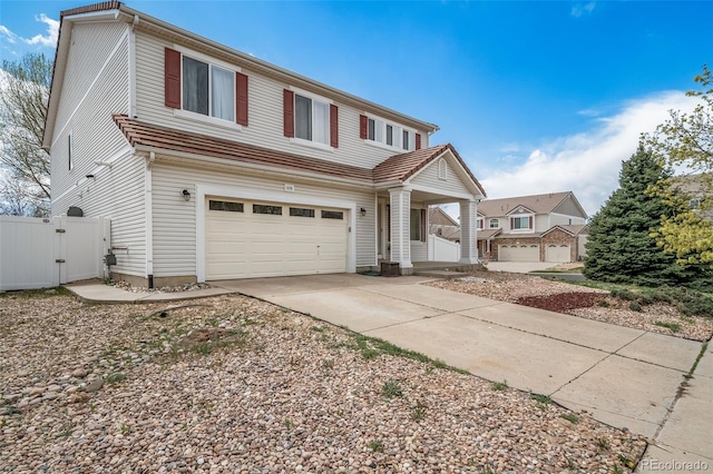 traditional home with a garage, a gate, concrete driveway, fence, and covered porch