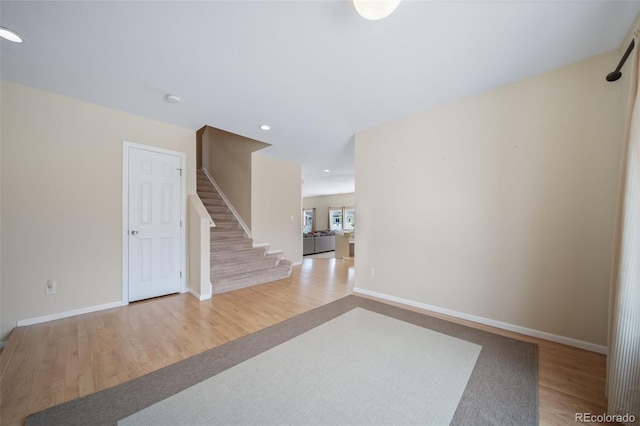 empty room with stairs, wood finished floors, baseboards, and recessed lighting