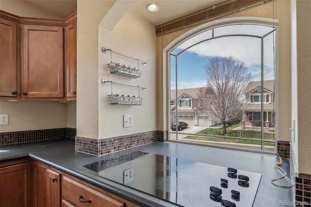kitchen with black electric cooktop, dark countertops, and brown cabinetry
