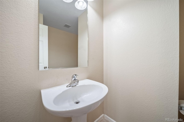 bathroom featuring a sink and a textured wall