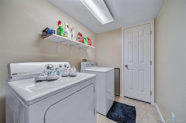 clothes washing area featuring washing machine and clothes dryer, light tile patterned flooring, and baseboards