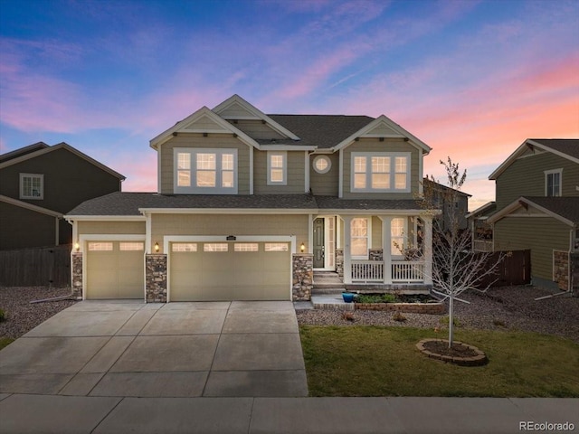 craftsman-style house featuring a lawn, concrete driveway, a porch, and stone siding