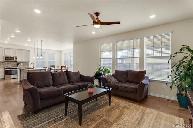 living area with baseboards, recessed lighting, wood finished floors, and a wealth of natural light