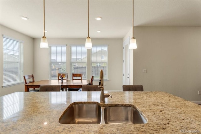 kitchen with recessed lighting, a sink, hanging light fixtures, and light stone countertops