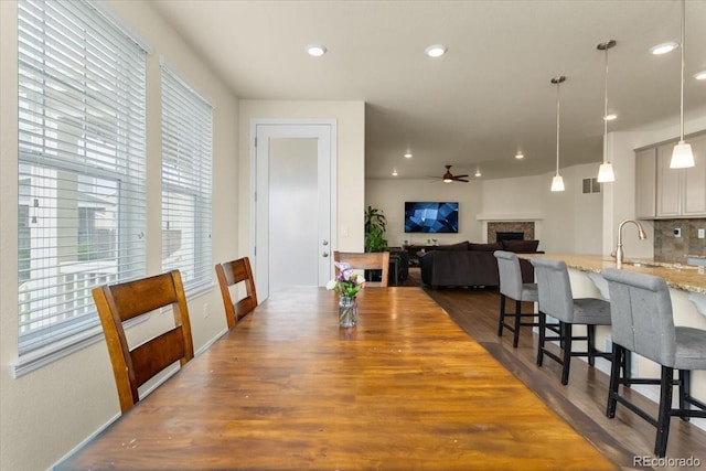 dining room featuring ceiling fan, visible vents, a wealth of natural light, and dark wood-type flooring