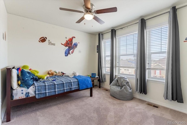 carpeted bedroom with a ceiling fan, baseboards, visible vents, and multiple windows