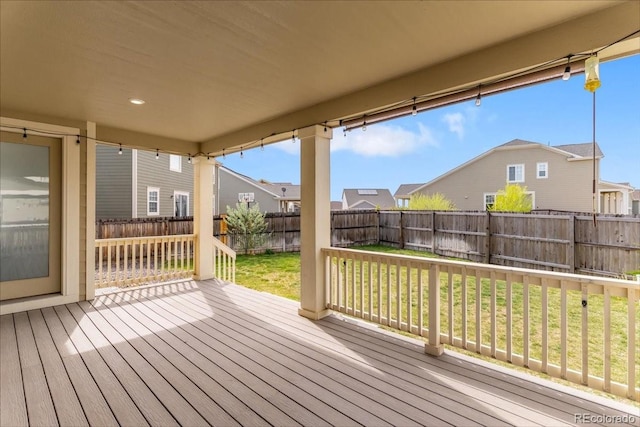 wooden terrace featuring a lawn, a fenced backyard, and a residential view
