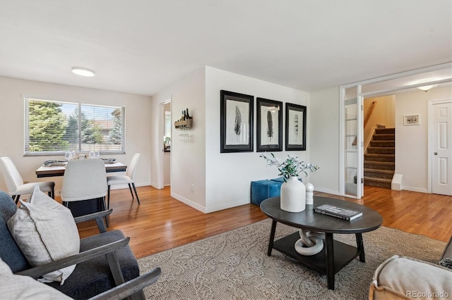 living room with light wood-style flooring, stairway, and baseboards