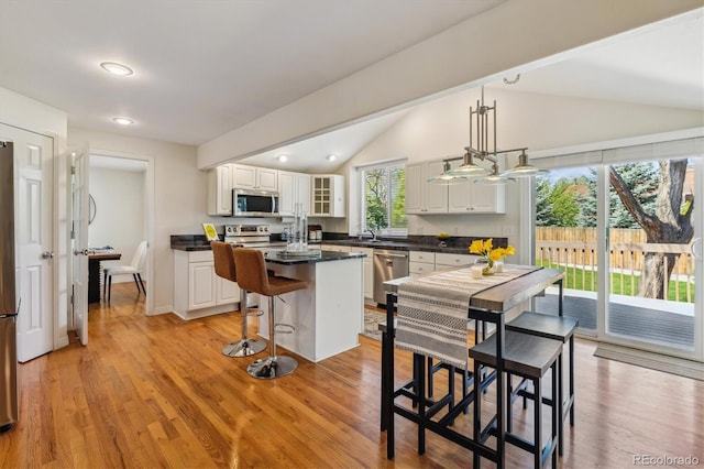 kitchen featuring stainless steel appliances, dark countertops, vaulted ceiling, white cabinets, and glass insert cabinets