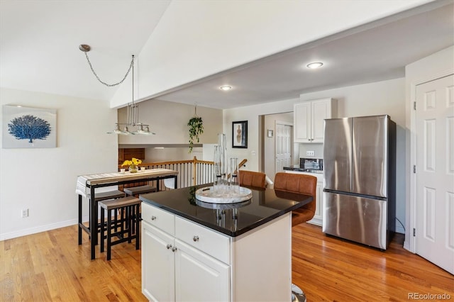 kitchen featuring freestanding refrigerator, white cabinetry, light wood-type flooring, a center island, and recessed lighting