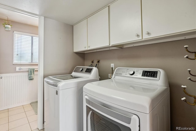 laundry area with independent washer and dryer, cabinet space, a wainscoted wall, and light tile patterned floors