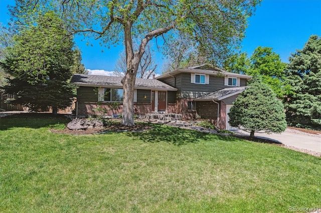 tri-level home featuring brick siding, a front lawn, and driveway