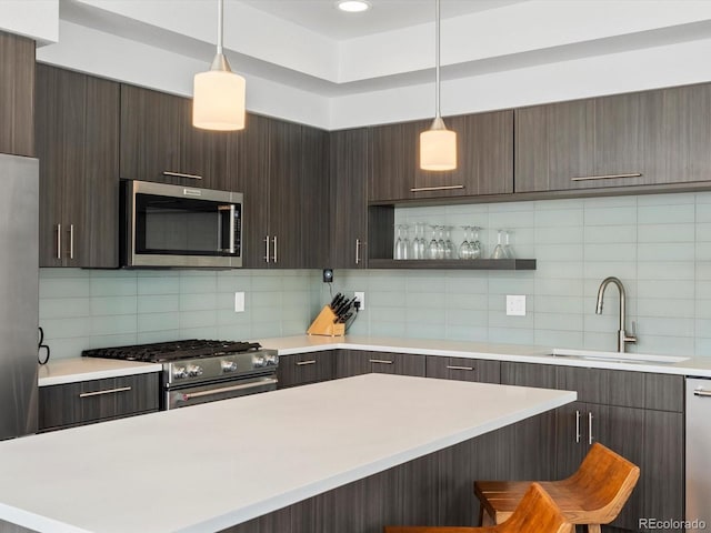 kitchen with appliances with stainless steel finishes, a sink, light countertops, and dark brown cabinets