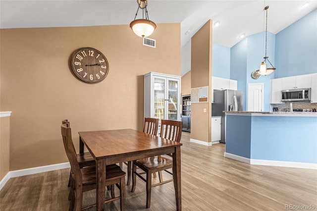 dining area featuring light hardwood / wood-style flooring and high vaulted ceiling