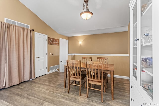 dining space with vaulted ceiling and hardwood / wood-style floors