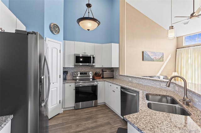 kitchen featuring sink, white cabinets, hanging light fixtures, appliances with stainless steel finishes, and a high ceiling