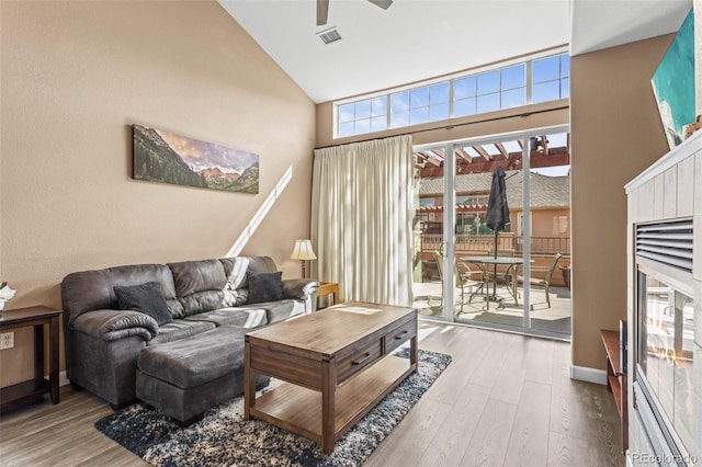 living room with ceiling fan, hardwood / wood-style flooring, plenty of natural light, and high vaulted ceiling