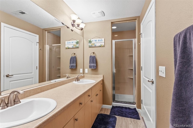 bathroom with a textured ceiling, vanity, and a shower with shower door