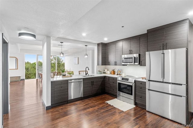 kitchen featuring appliances with stainless steel finishes, sink, dark hardwood / wood-style floors, and decorative light fixtures