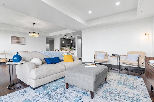 living room with dark wood-type flooring, a raised ceiling, and an inviting chandelier