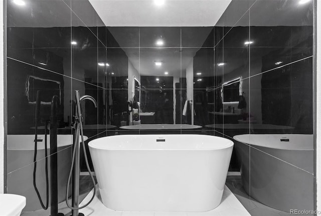 bathroom featuring a bath and tile walls