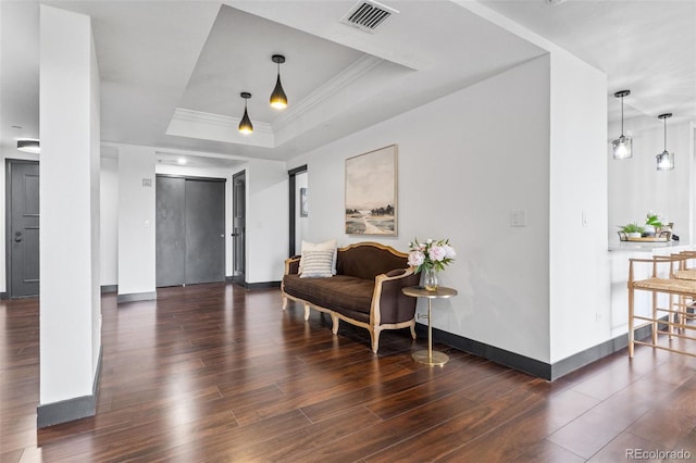 living area featuring a raised ceiling, ornamental molding, and dark hardwood / wood-style flooring