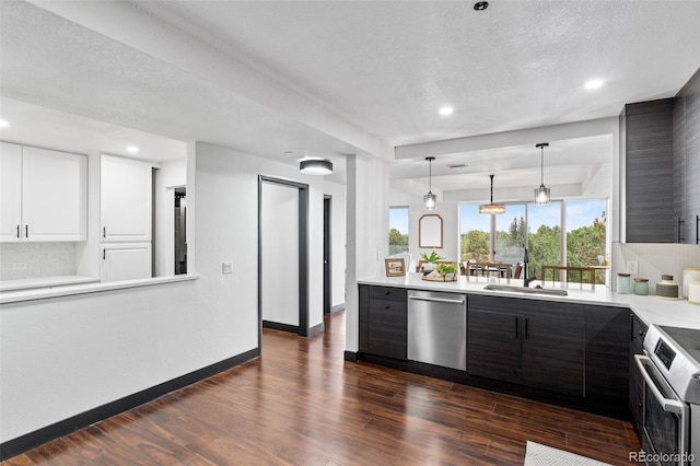 kitchen featuring appliances with stainless steel finishes, decorative light fixtures, sink, white cabinets, and dark hardwood / wood-style flooring