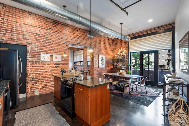 kitchen with brick wall, brown cabinets, black electric range oven, and freestanding refrigerator