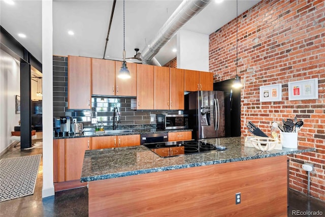 kitchen with a towering ceiling, brick wall, appliances with stainless steel finishes, a sink, and backsplash