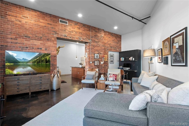 living room featuring finished concrete floors, a high ceiling, visible vents, and brick wall