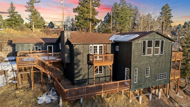 back house at dusk with a balcony and a deck