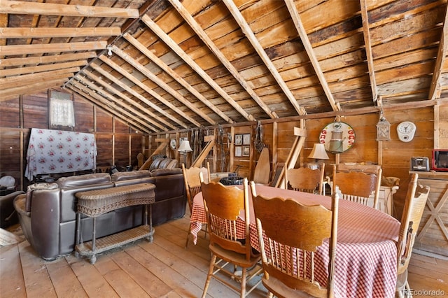 dining space with wooden walls, hardwood / wood-style floors, wooden ceiling, and vaulted ceiling