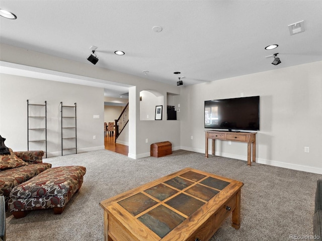 carpeted living area with stairway, arched walkways, baseboards, and recessed lighting