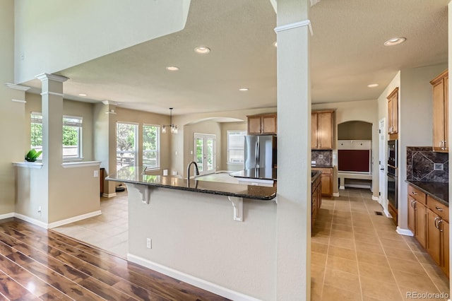 23029 Cleveland Dr, Parker, CO 80138 - kitchen featuring appliances with stainless steel finishes, decorative columns, a breakfast bar area, recessed lighting, and tasteful backsplash