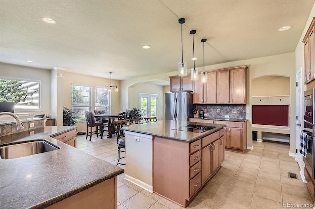 23029 Cleveland Dr, Parker, CO 80138 - kitchen with freestanding refrigerator, black electric stovetop, a kitchen island, arched walkways, and tasteful backsplash