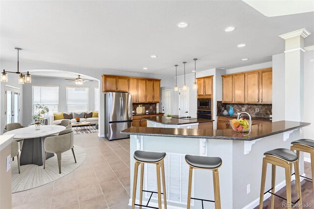 23029 Cleveland Dr, Parker, CO 80138 - kitchen featuring appliances with stainless steel finishes, decorative backsplash, a kitchen breakfast bar, recessed lighting, and brown cabinets