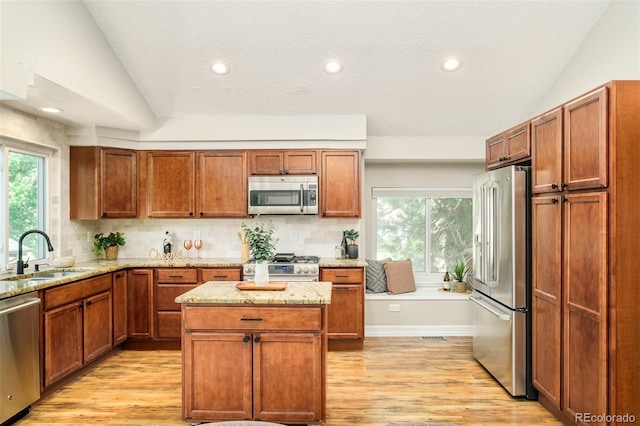 19595 N Mitchell Dr, Denver, CO 80249 - kitchen with appliances with stainless steel finishes, light wood-style floors, light stone counters, tasteful backsplash, and vaulted ceiling