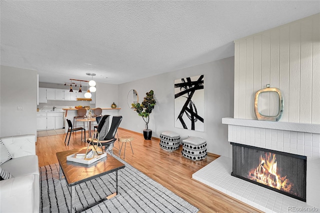 living room with light hardwood / wood-style floors, a textured ceiling, sink, and a fireplace