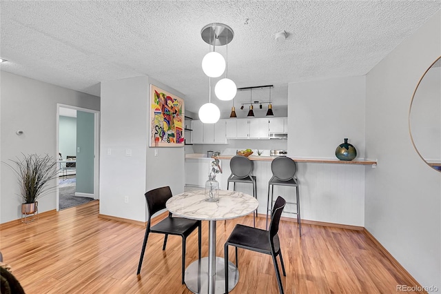 dining area with a textured ceiling and light wood-type flooring