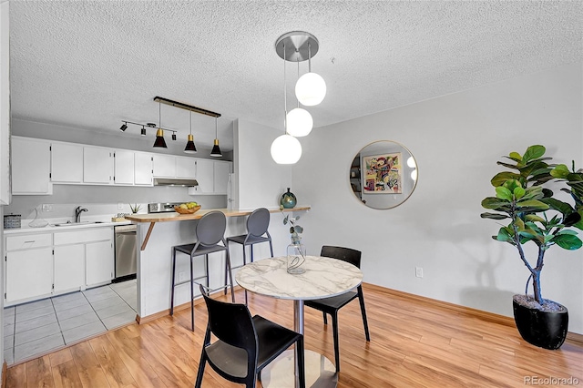 dining room featuring sink, light hardwood / wood-style flooring, and a textured ceiling