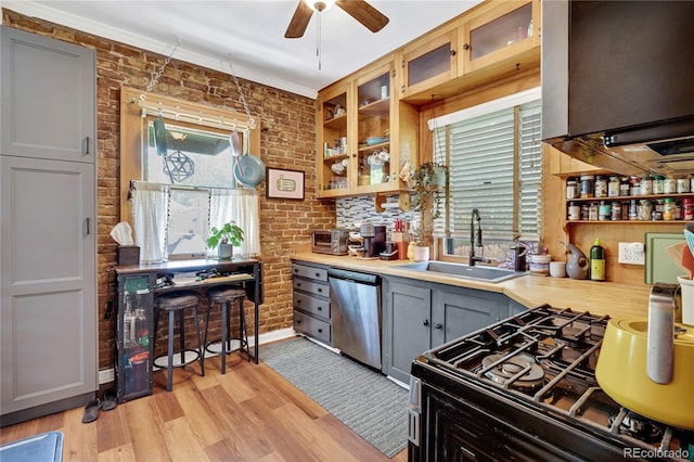 2236 Forest St, Denver, CO 80207 - kitchen featuring stainless steel dishwasher, a sink, light countertops, light wood-type flooring, and black gas range