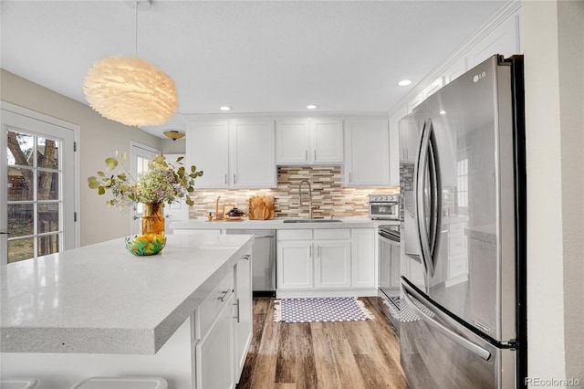 kitchen with white cabinetry, stainless steel appliances, sink, and pendant lighting