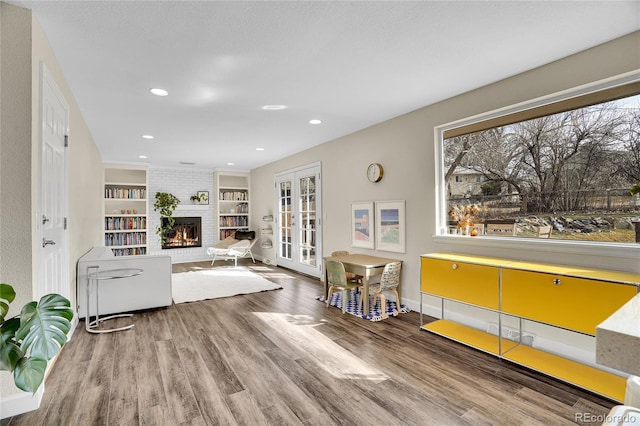 living room featuring french doors, wood-type flooring, a fireplace, and built in features