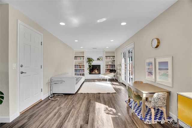 living room with french doors, built in shelves, a brick fireplace, and hardwood / wood-style flooring