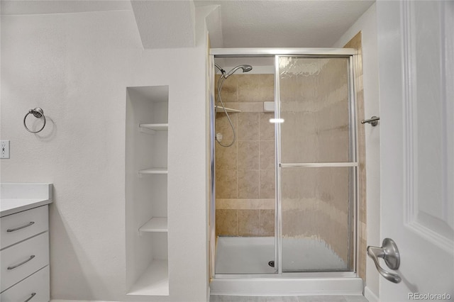 bathroom with walk in shower, vanity, and a textured ceiling