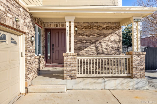 view of exterior entry featuring a garage and covered porch