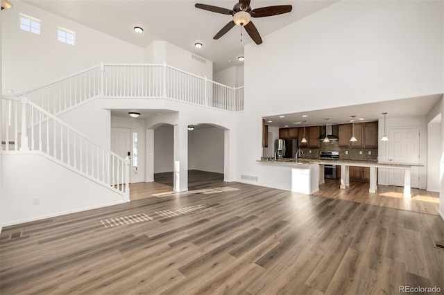 unfurnished living room featuring ceiling fan, a towering ceiling, and dark hardwood / wood-style floors